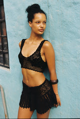 Person wearing a black crochet outfit lying on a blue surface